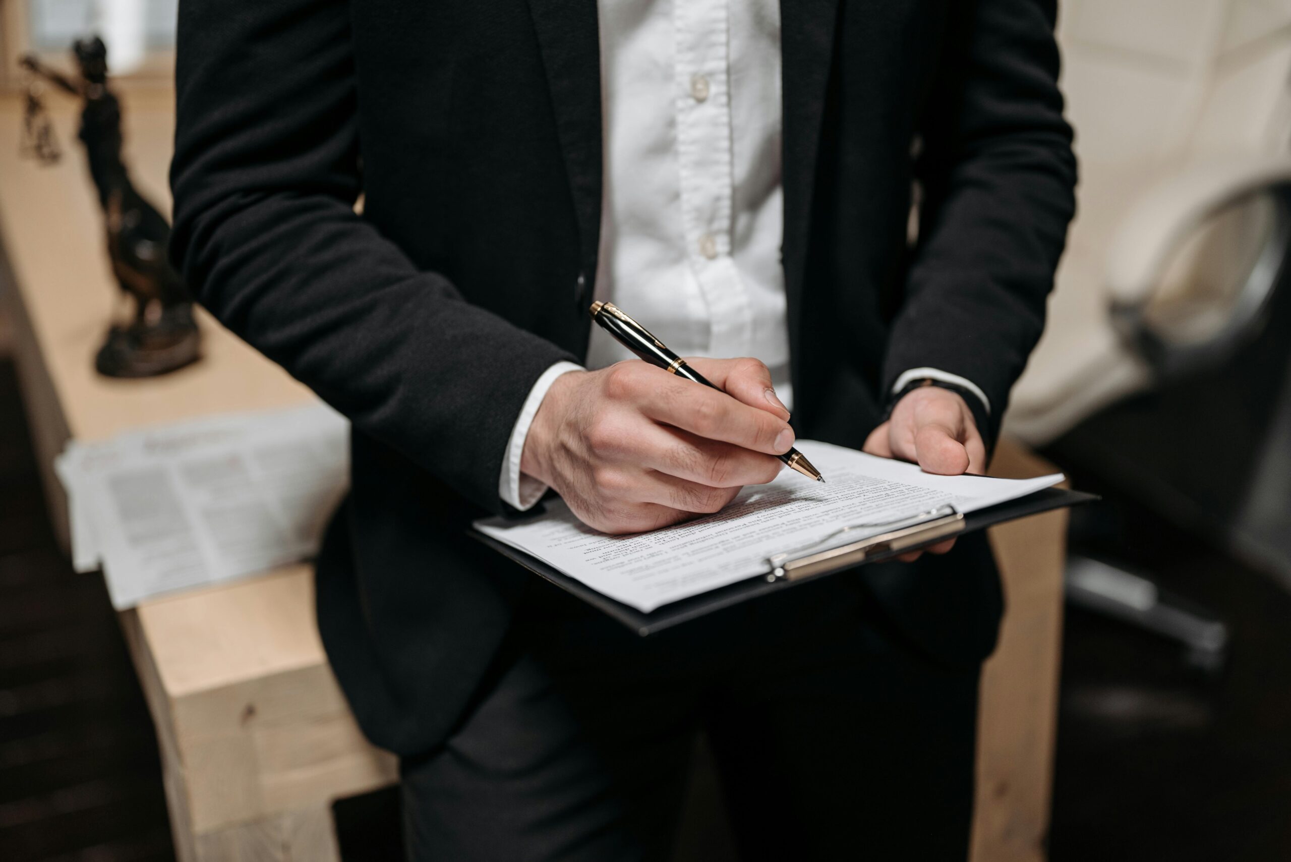 Business professional signing a contract on a clipboard at the office.